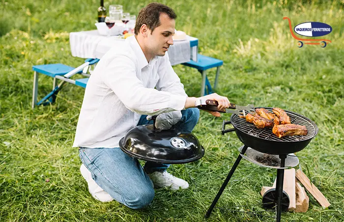 Hombre asando cortes de carne en un asador portátil