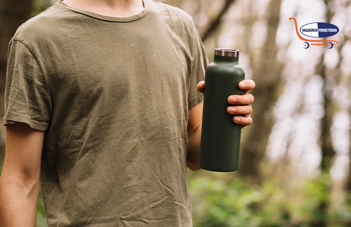 Joven sosteniendo un termo para bebidas en un entorno natural